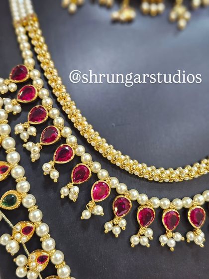 The teardrop-shaped ruby stones and delicate pearls give this bridal set a rich and elegant feel.