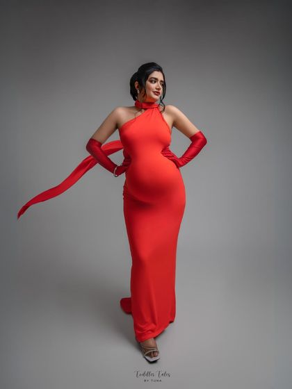 Modern muse in red. This halter-neck gown with matching gloves and a flowing ribbon creates a chic, contemporary silhouette. It’s a perfect example of how maternity style can be both sophisticated and powerful.