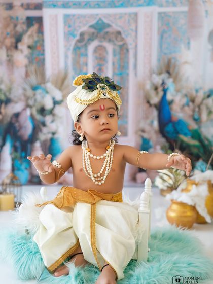 A beautiful portrait of a baby boy in his Krishna costume. The soft blue and gold tones of the backdrop create a truly divine atmosphere.