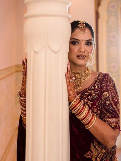 A bride peeks from behind a pillar, a playful yet elegant portrait that uses the architecture of the venue to create a unique shot.