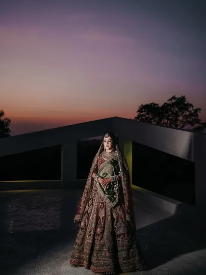An artistic bridal portrait against the dramatic twilight sky. I use light and shadow to create stunning, magazine-worthy images that highlight the bride's elegance and the grandeur of her attire.