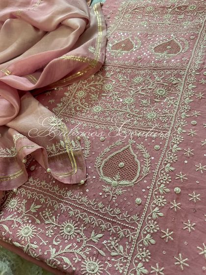 A detailed flat-lay of the blush pink suit, showcasing the intricate jaal work on the kurta and the coordinated, embellished dupatta.