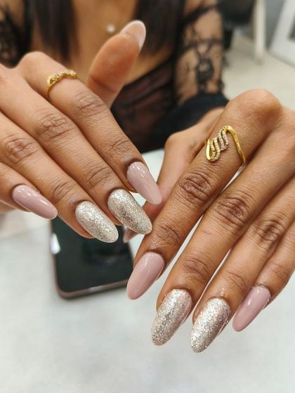 A chic and modern nail set featuring a neutral beige polish paired with a brilliant silver glitter accent nail. This combination is perfect for a sophisticated look with a touch of glamour.