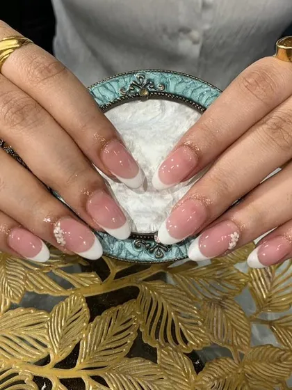 A beautiful and clean classic French manicure on almond-shaped nails, with tiny flower gem accents for a subtle touch of sparkle.