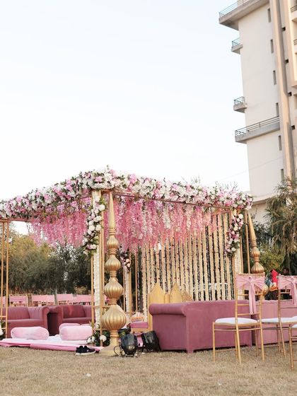 A wider view of a pastel pink mandap setup, showing the coordinated lounge seating for guests, creating a cohesive and comfortable experience.