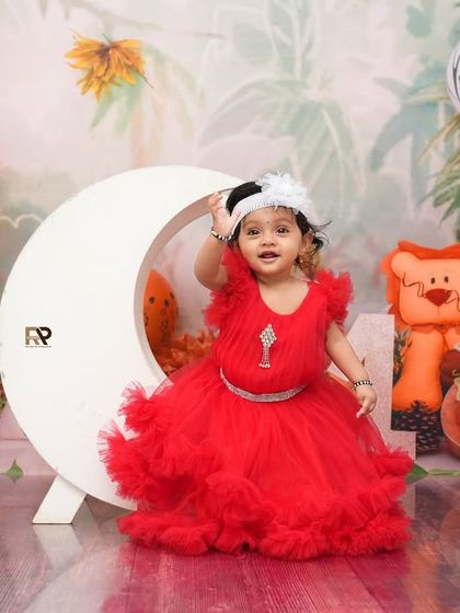 A close-up of the little girl in the red dress, adjusting her headband. The animal-print balloons and jungle backdrop add to the wild and whimsical theme.