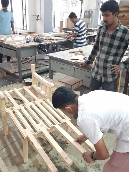 A team of students works on assembling a large wooden frame, ensuring all parts fit together correctly before final fastening.