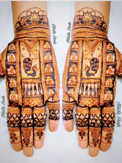 A detailed Indian mehendi design with a prominent peacock figure. The fine line work and checkerboard patterns showcase the intricacy of the art.