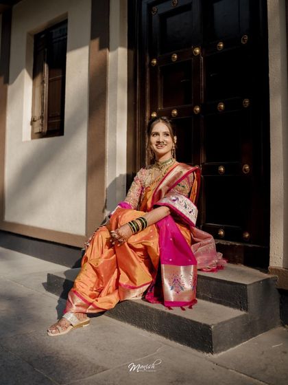 A candid portrait of the Marathi bride, sitting on the steps and smiling, looking radiant in her traditional wedding attire.