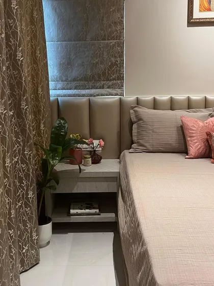This bedroom design uses a neutral, earthy color palette to create a calming environment. The upholstered headboard extends across the wall, creating a seamless and sophisticated look.