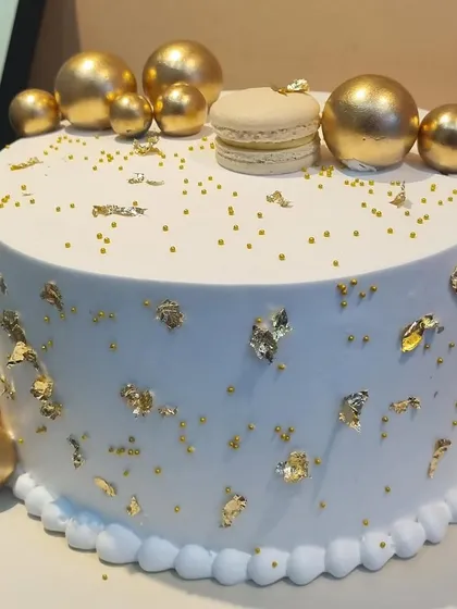 This white and gold themed cake is the epitome of royal elegance. Flavored with Lotus Biscoff and decorated with gold leaf, macarons, and golden spheres, it adds a touch of luxury to any special occasion.