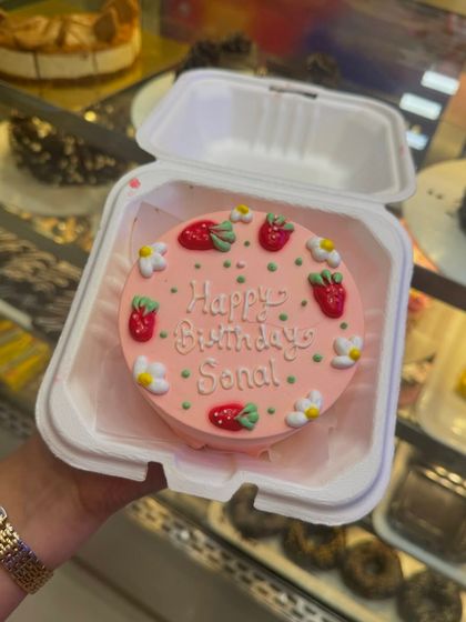 A lovely pink bento cake decorated with cute fondant strawberries and daisies. It's a fresh and cheerful design, personalized for Sonal's birthday.