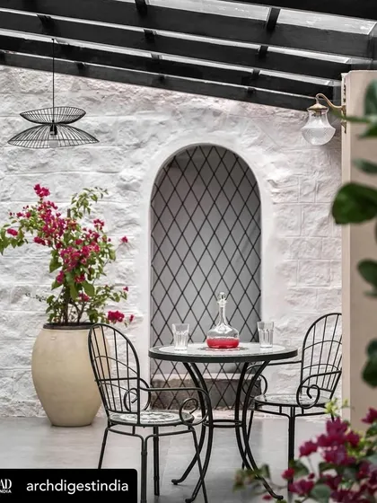 I design spaces that invite you to relax and connect with nature. This serene patio, part of a large holiday home, was designed as a quiet escape, blending a rough, white-washed stone wall with elegant wrought-iron furniture and vibrant bougainvillea. It’s a perfect example of creating a peaceful outdoor oasis.