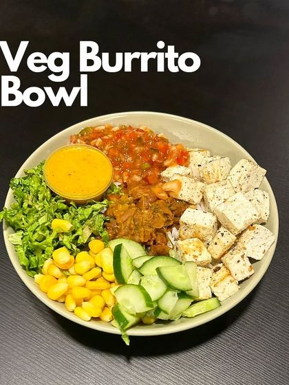 Our Veg Burrito Bowl is a vegetarian delight. This image shows the colorful mix of paneer, refried beans, corn, cucumber, and lettuce, served with a side of our tangy mango chipotle dressing.