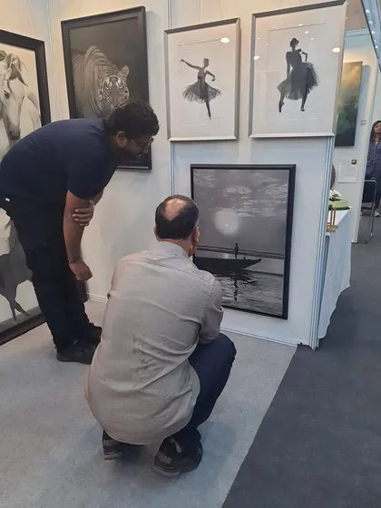 A potential collector taking a close look at my seascape artwork during a show.