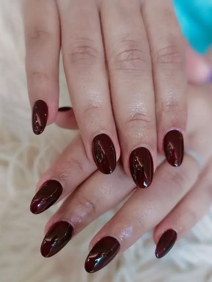 A beautiful set of glossy, deep maroon nails in a classic almond shape. A sophisticated choice for any season.