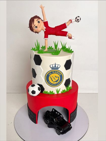 A full view of the football and Ferrari-themed cake, showcasing the dynamic pose of the football player topper.