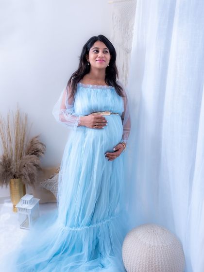 A candid-style lifestyle portrait in our studio. The mom-to-be looks happy and relaxed in a light blue gown.