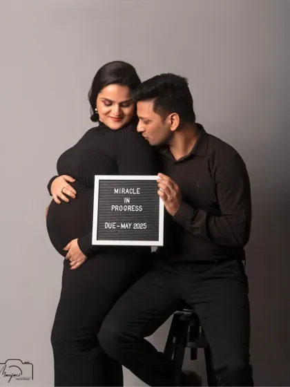 A sweet and intimate moment, with the partner whispering to the baby bump. The simple black outfits and grey background are modern and timeless.