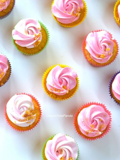 A close-up of the pink swirl cupcakes, showing the simple rosette piping and gold flake details.