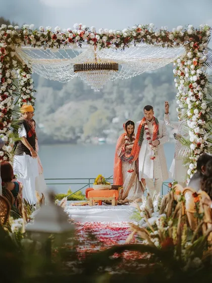 A wide shot of a breathtaking lakeside mandap, showcasing the scale and beauty of a destination Hindu wedding.