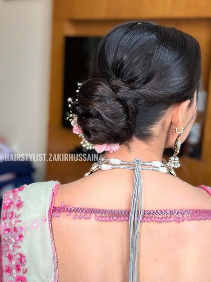 Another angle of the sleek low bun with pink carnations, showing how the flowers are placed to complement the shape of the updo.
