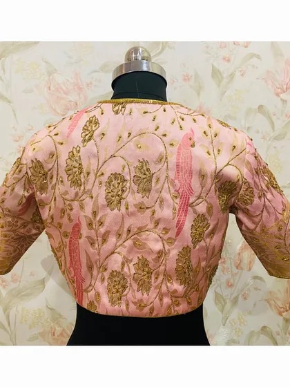 The back of the pink brocade blouse, showcasing a beautiful pattern of embroidered vines and parrots, a classic and charming design.