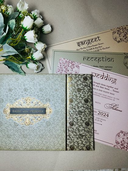 A full view of a modern invitation suite with a textured brocade cover and matching inserts for Wedding, Reception, and Sangeet.
