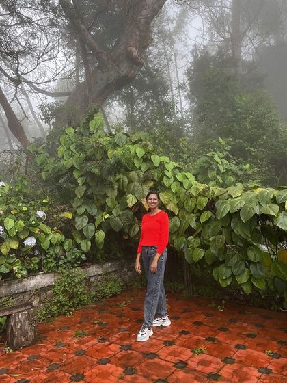 A trekker posing in a lush green garden in Kodaikanal.