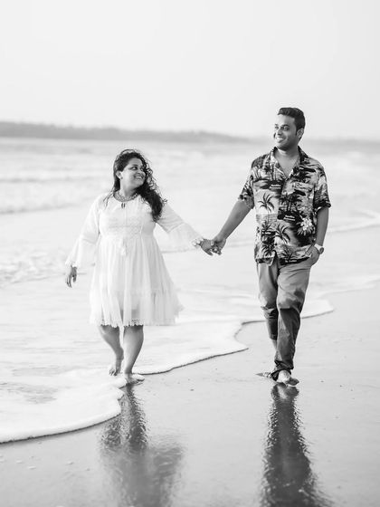 Eva and Raphael's pre-wedding walk on the beach, captured in crisp black and white. Their contrasting outfits and joyful expressions stand out beautifully.