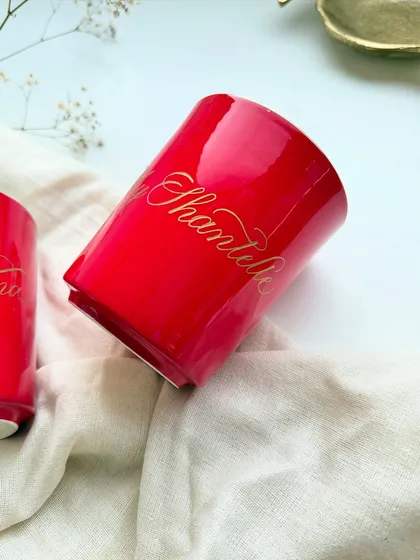 A close-up of a personalized red mug. The gold script catches the light beautifully, turning a simple mug into a cherished item.