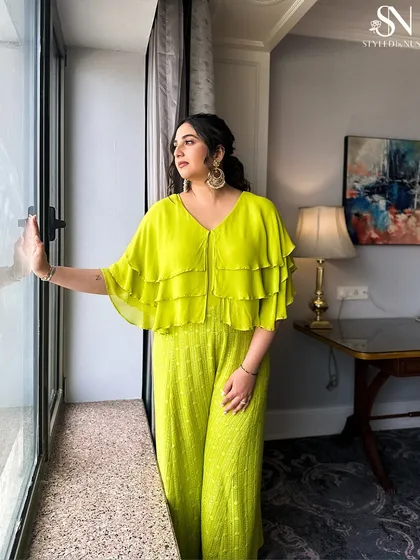 A modern Mehendi look with a textured, wavy hairstyle that complements this bold, neon green jumpsuit.