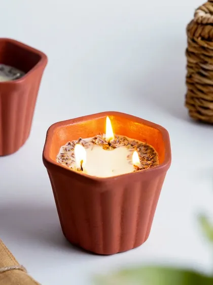 A close-up of a lit terracotta candle, creating a warm and inviting glow. This shot focuses on the cozy ambiance that a scented candle can bring to a space.