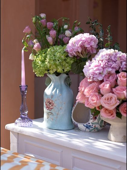 A collection of ceramic vases filled with hydrangeas and roses, part of the decor for the "Art Day Out" brunch.