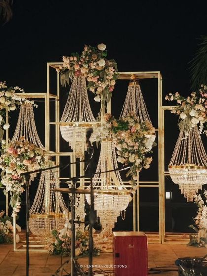 The stage for the live band, featuring a backdrop of modern gold frames holding cascading crystal chandeliers and floral arrangements.