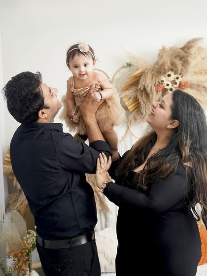A candid and joyful family moment. The father lifts his daughter, and the mother's laugh makes this a wonderfully authentic and happy portrait.