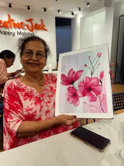 This student is delighted with her finished floral painting, a lovely composition of pink magnolias created during a relaxing workshop session.