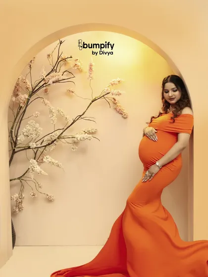 The same beautiful pose from a slightly different angle, highlighting the graceful lines of the dress and the baby bump.