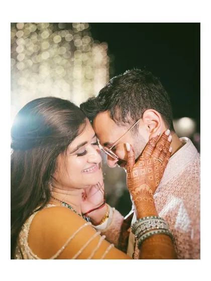 An intimate close-up of Avi and Devika. The soft lighting and bokeh background create a dreamy feel, focusing on her intricate henna and their gentle connection.