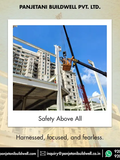 Safety above all. A worker, securely harnessed in a lift basket, works at height to connect the steel framework, reflecting our unwavering commitment to safe construction practices on all our sites.