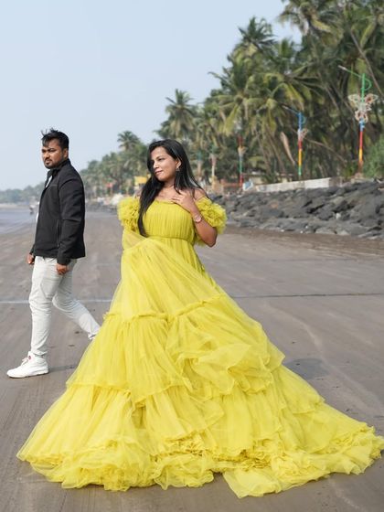 A candid shot of the couple on a beach, with the woman in the flowing yellow gown.
