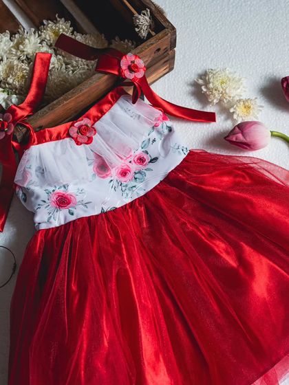 A flat-lay of the red and white party dress, highlighting the delicate floral details on the bodice and straps.