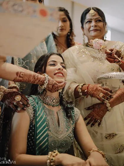A bride being pampered and blessed by the women in her family. The multiple hands reaching out to her create a powerful image of love and community.