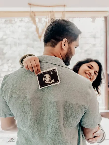 Sometimes the simplest ideas are the most powerful. A sweet hug from behind with the sonogram photo says everything about their love and excitement.