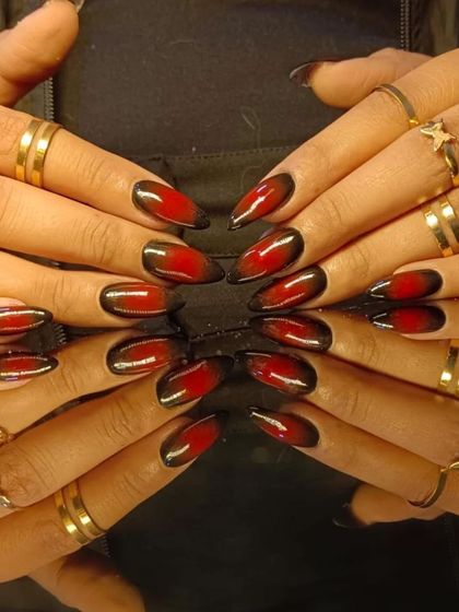 A full view of the fiery red and black cat-eye manicure, styled with gold rings.