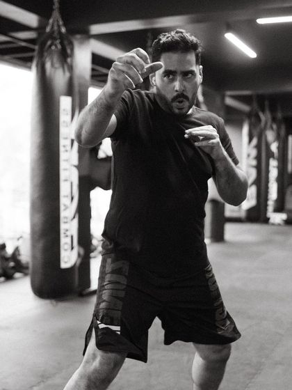 A coach demonstrates a fighting stance, showing the athletic posture required for combat.