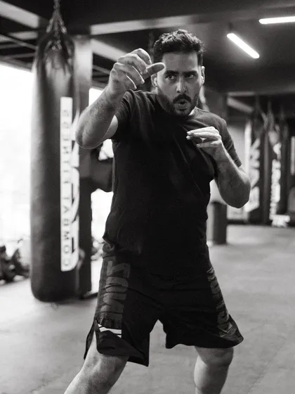 A coach demonstrates a fighting stance, showing the athletic posture required for combat.