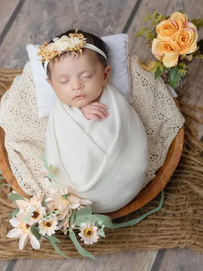 A rustic and gentle setup with a newborn sleeping in a wooden bowl on a jute mat.