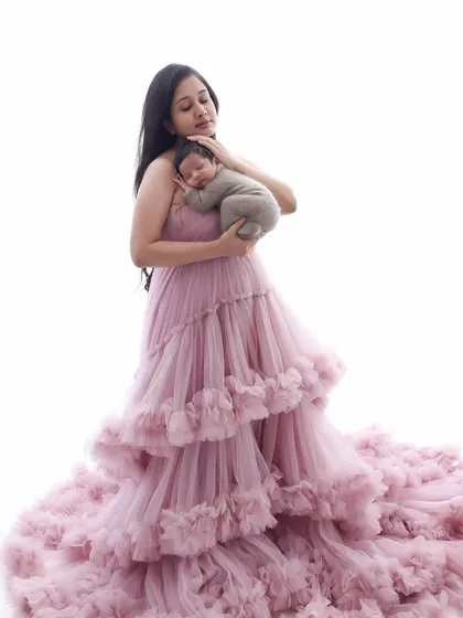 A mother's embrace, a world of love. This portrait, with the mother in a beautiful flowing gown, captures the elegance and emotion of her new role. The focus is on the tender connection with her newborn.