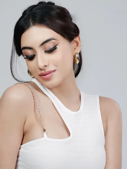 A close-up beauty shot focusing on the model's elegant makeup and the details of her white dress.